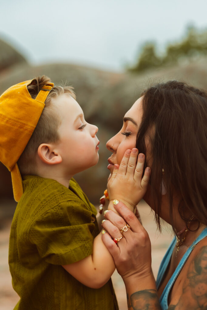 Elephant Rocks State Park Family Photographers capture little boy putting his hands on his mom's cheeks as he goes to kiss her nose during family session.