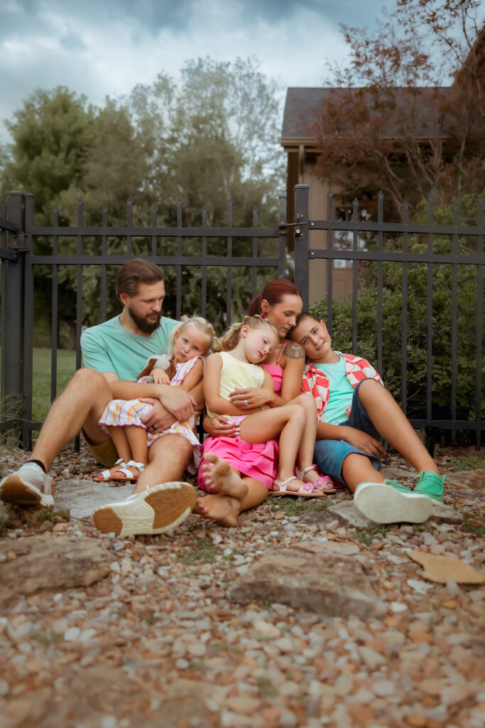 When searching Family Photos Near Me in Kansas City I hope you'll find these beautiful backyard snuggle photos of a family in colorful summer colors piled up in their backyard landscape.