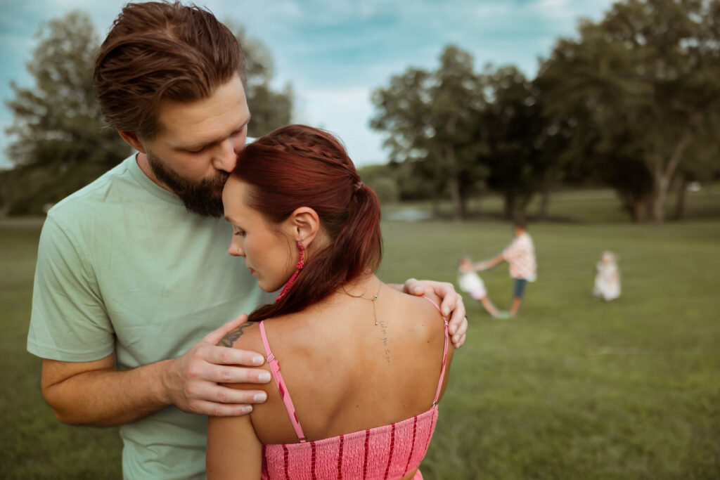 When searching Family Photos Near Me in Kansas City I hope you'll find this photo of mom and dad sharing a moment while their three children play in the background of their back yard.