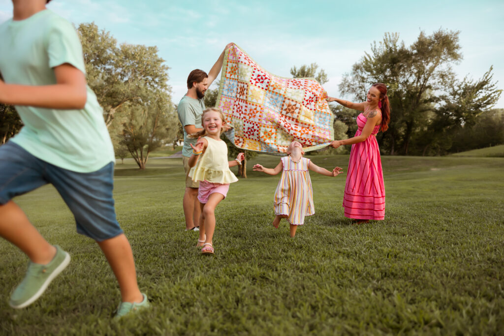If you search Family Photos Near Me in Kansas City you'll find photographers that use colorful blankets to get families to play together during their family backyard photosession.
